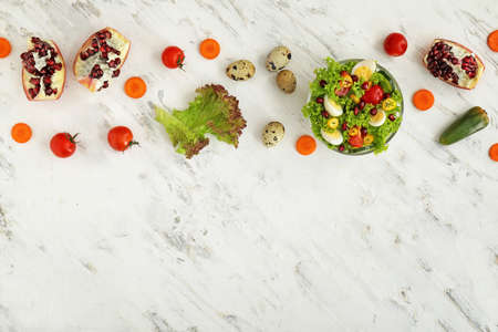 Bowl with quail eggs and vegetables on light background