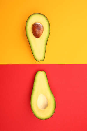 Halves of ripe avocado on color backgroundの写真素材