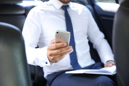 Successful businessman with mobile phone in modern carの写真素材