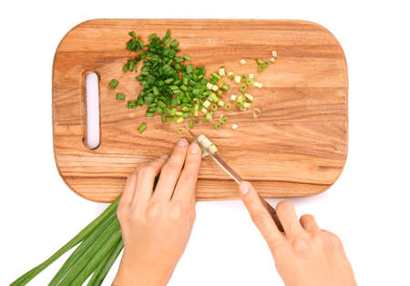 Woman cutting green onion on board against white background, top view