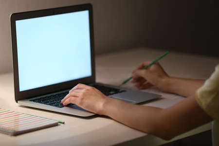 Woman working on laptop at table in evening