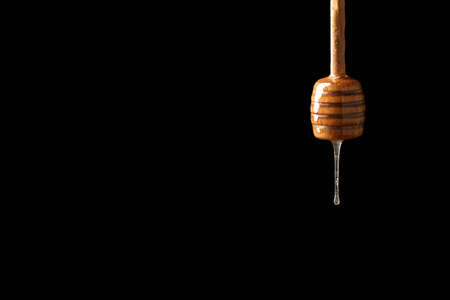 Dipper with tasty honey on dark background