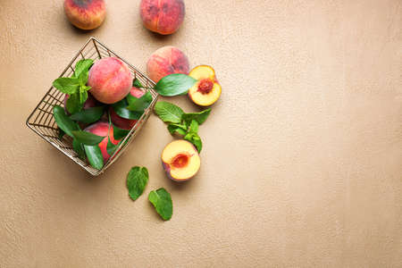 Basket with tasty peaches and mint on color backgroundの写真素材
