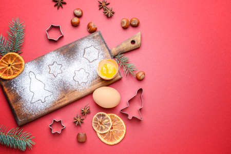 Wooden board with cookie cutters and ingredients on color backgroundの写真素材