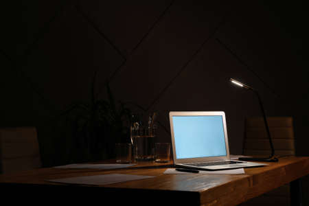 Modern workplace with laptop in eveningの写真素材