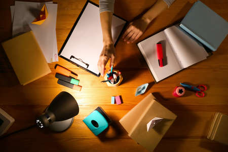 Woman working at table late in evening, top view