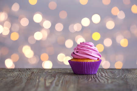 Tasty Birthday cupcake on table against defocused lightsの写真素材