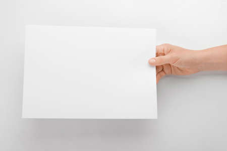 Female hand with empty sheet of paper on white background