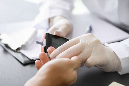 Doctor checking blood sugar level of diabetic patient in clinic, closeupの写真素材