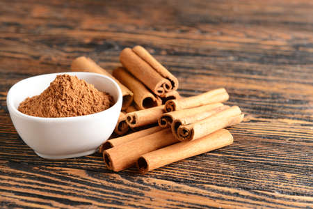 Aromatic cinnamon sticks and powder on wooden table