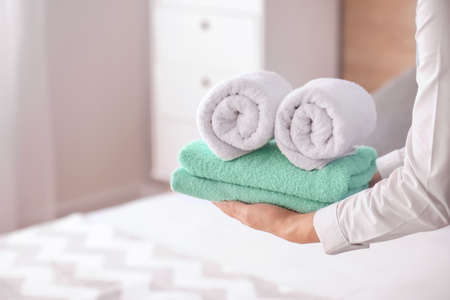 Female housekeeper with clean towels in bedroomの写真素材