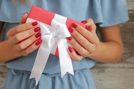 Woman with beautiful manicure holding gift box, closeup