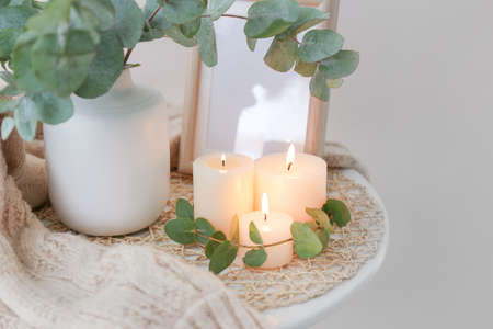 Beautiful burning candles and vase with eucalyptus branches on tableの写真素材