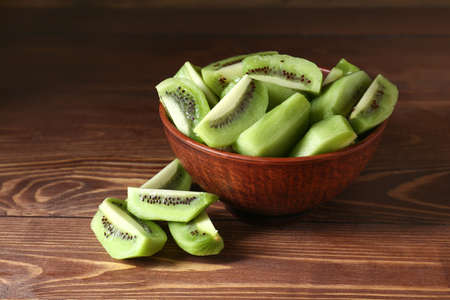 Bowl with tasty cut kiwi on wooden backgroundの写真素材