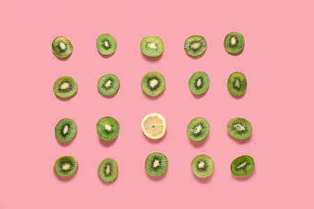 Many slices of kiwi and one lemon on color background. Concept of uniquenessの写真素材