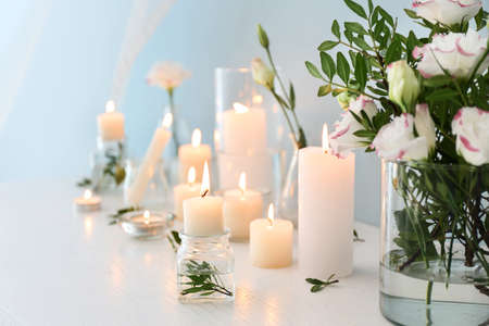 Beautiful burning candles and flowers on tableの写真素材