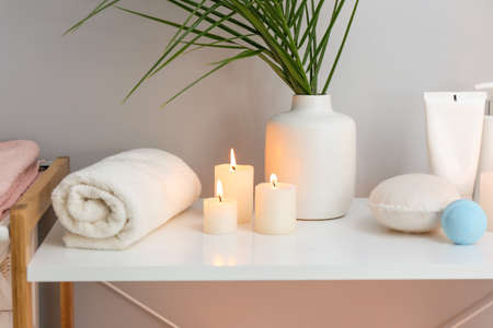 Beautiful burning candles and cosmetics on stand in bathroomの写真素材