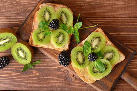Tasty sandwiches with kiwi and blackberry on wooden boardの写真素材