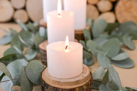 Beautiful burning candles and eucalyptus branches on table, closeupの写真素材
