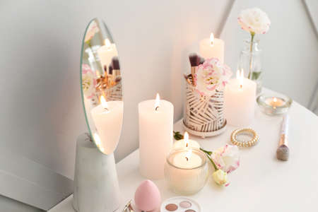 Beautiful burning candles and cosmetics on dressing tableの写真素材