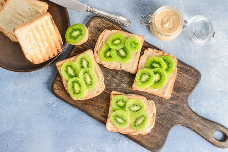 Tasty sandwiches with kiwi and peanut butter on tableの写真素材