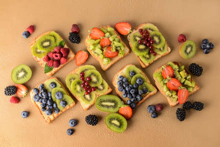 Tasty sandwiches with kiwi and berries on color backgroundの写真素材