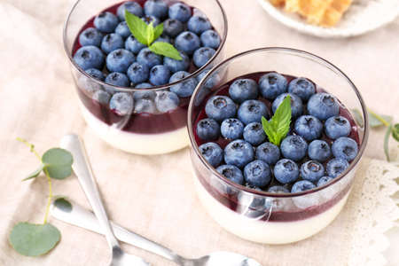 Glasses with blueberry dessert on table, closeup