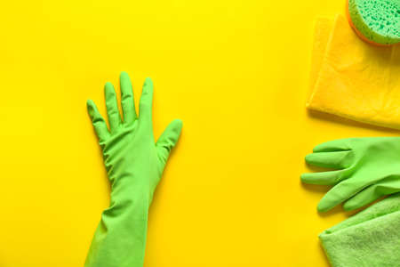 Hand in glove with cleaning supplies on color backgroundの写真素材