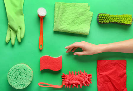 Female hand with cleaning supplies on color background