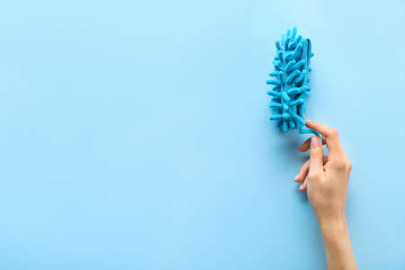 Female hand holding dust brush on color backgroundの写真素材