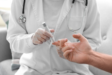 Doctor taking blood sample of diabetic man at home, closeupの写真素材
