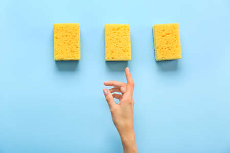 Female hand with cleaning sponges on color backgroundの写真素材
