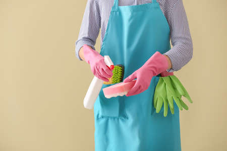 Woman with cleaning supplies on color background, closeup