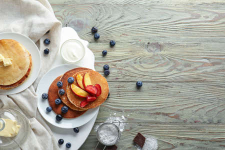 Tasty pancakes with berries and butter on wooden table