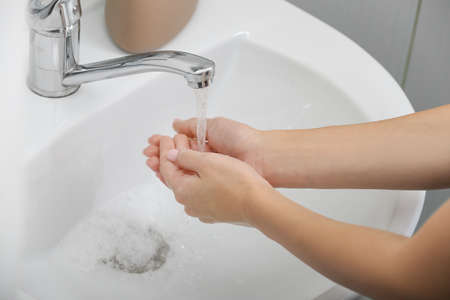 Young woman washing hands in sinkの写真素材