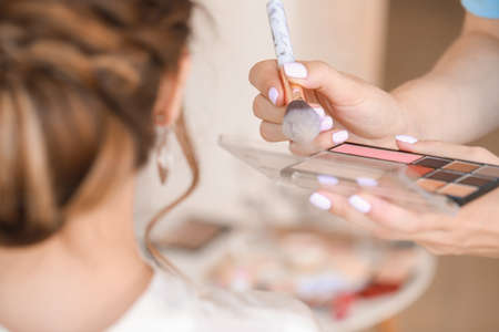 Professional makeup artist working with young bride at home, closeupの写真素材
