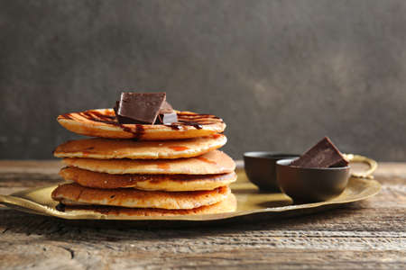 Tray with tasty pancakes and chocolate on wooden tableの写真素材