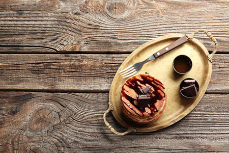 Tray with tasty pancakes and chocolate on wooden tableの写真素材
