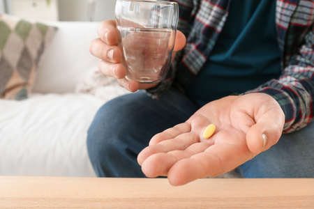 Elderly man taking medicine at home, closeup