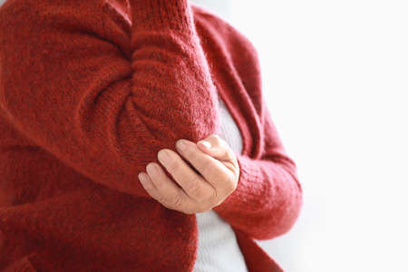 Senior woman suffering from pain in elbow at home, closeupの写真素材