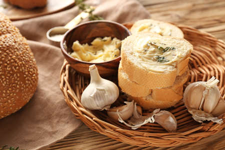 Slices of fresh bread with butter, herbs and garlic on table