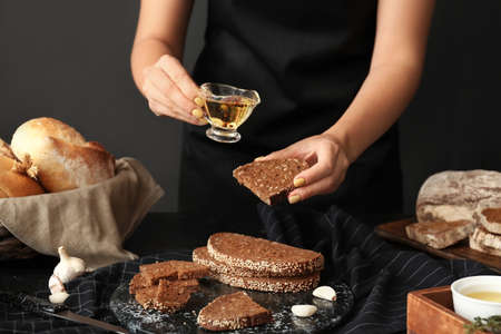 Woman pouring oil onto slice of bread, closeupの写真素材