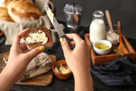 Woman spreading butter onto slice of fresh bread, closeupの写真素材