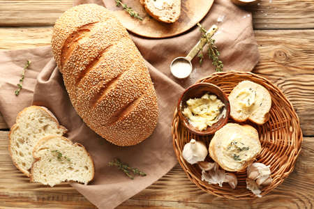 Slices of fresh bread with butter, herbs and garlic on table