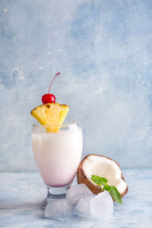Glass of tasty Pina Colada cocktail, ice cubes and coconut on table