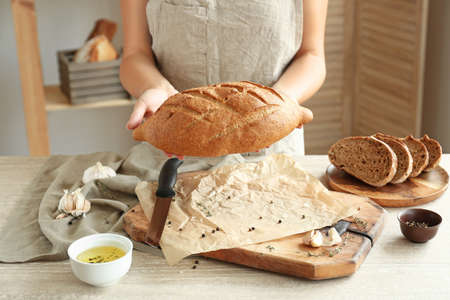 Woman with fresh bread in kitchen, closeup