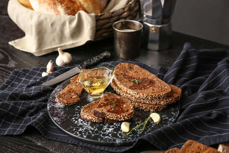 Board with slices of fresh bread, oil and spices on table