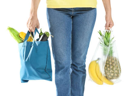 Woman with fresh vegetables and fruits in different bags on white background, closeup. Ecology...
