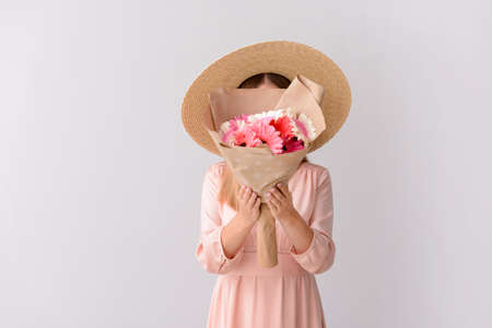 Woman with bouquet of beautiful gerbera flowers on light backgroundの写真素材