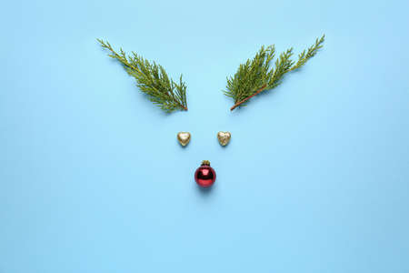 Funny deer face made of Christmas decor on color background